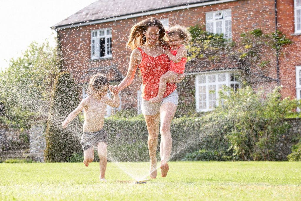 Family running through sprinklers in summer