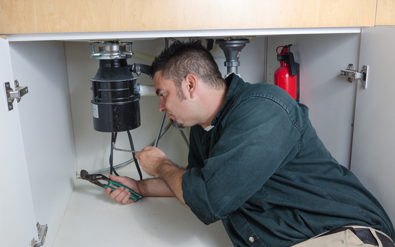 Plumber installing a garbage disposal